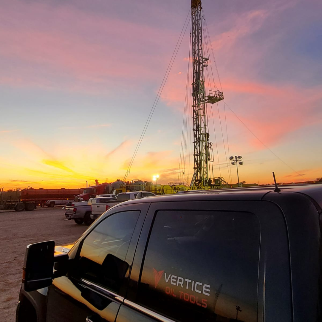 black truck with vertice oil tools logo on the back window. parked in from of a refrac tower.