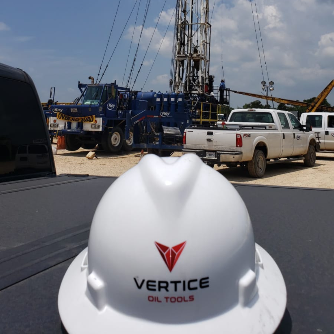 white vertice oil tools helmet on the ground in front of a refrac tower
